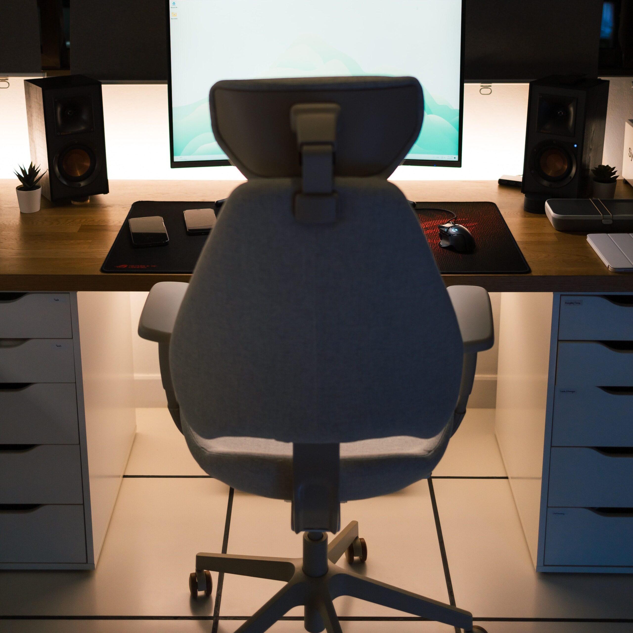 A stylish home office setup featuring an ergonomic chair, desk, and computer screen.