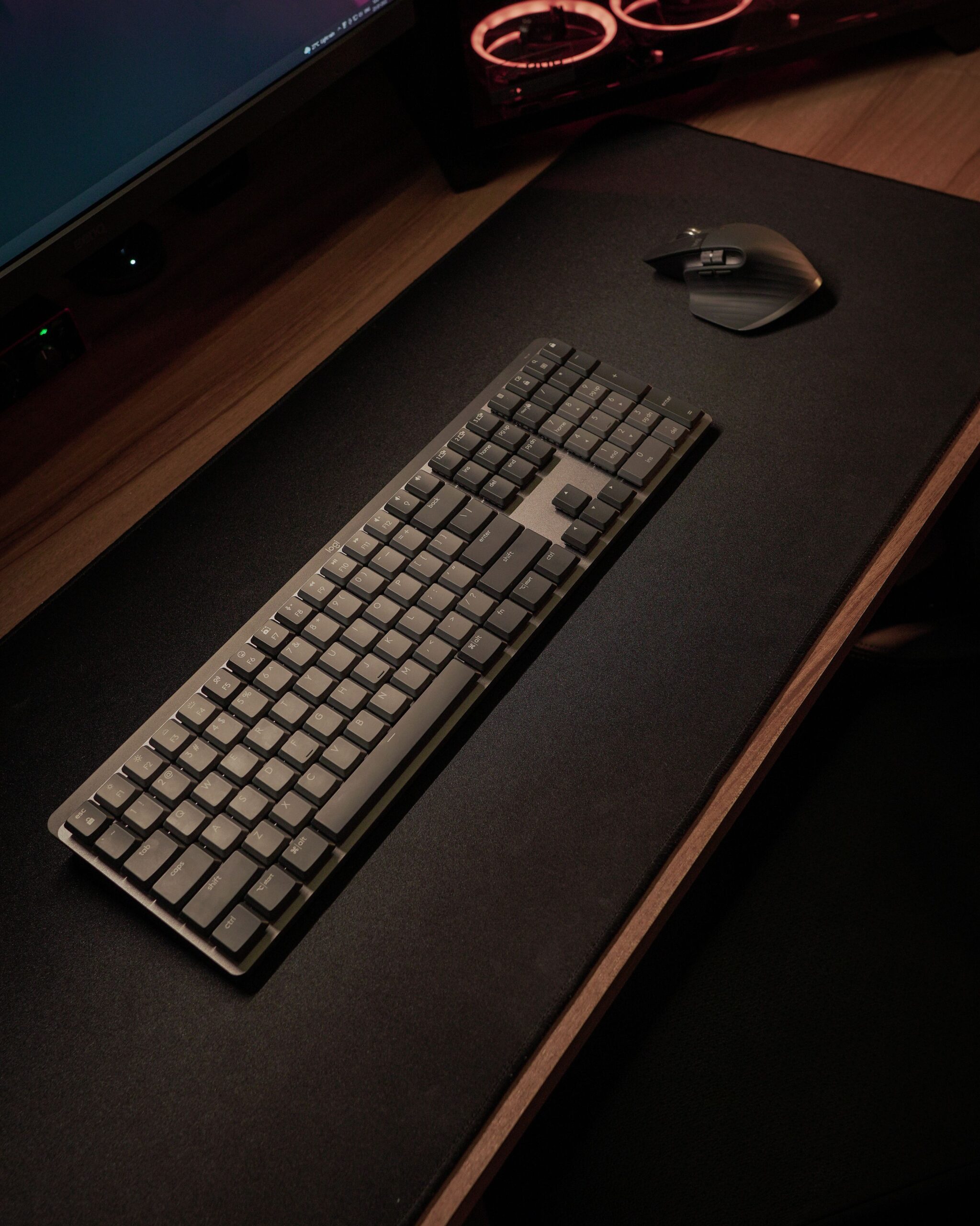 Sleek wireless keyboard and mouse setup on a minimalist desk with ambient lighting.