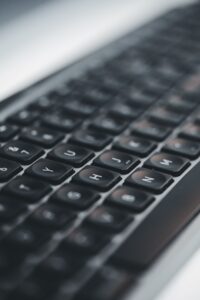 Detailed close-up of a black computer keyboard, highlighting keys in low light for a tech-focused shot.