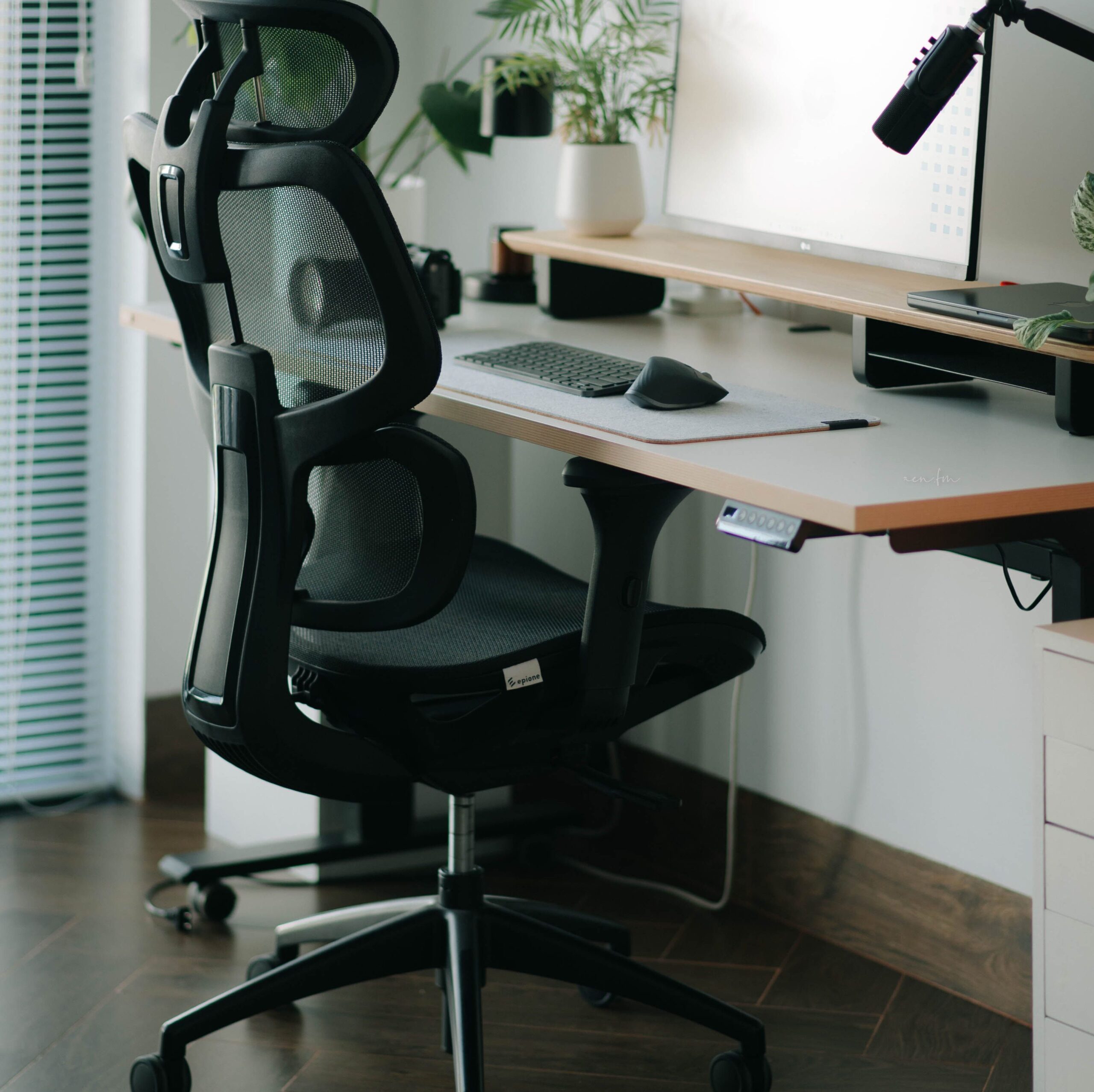 A sleek home office setup featuring a mesh ergonomic chair, desk, and greenery for a refreshing work environment.