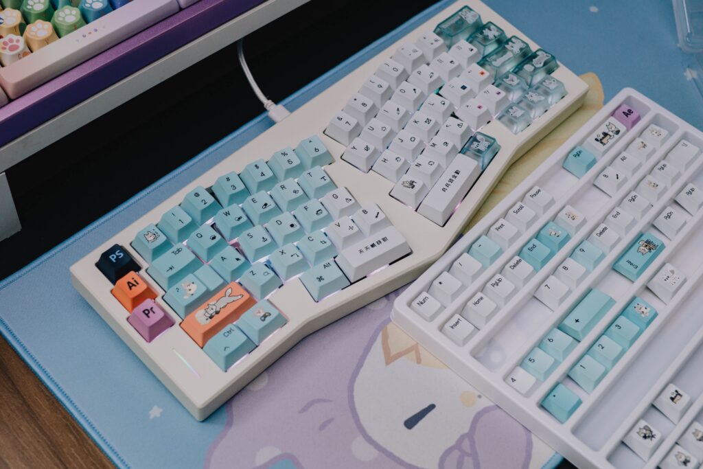 Two custom mechanical keyboards featuring pastel keycaps on a cute, themed desk mat.