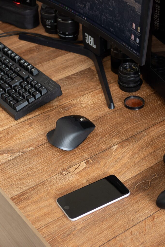 From above of black computer near smartphone and modern devices on desk in daylight at home
