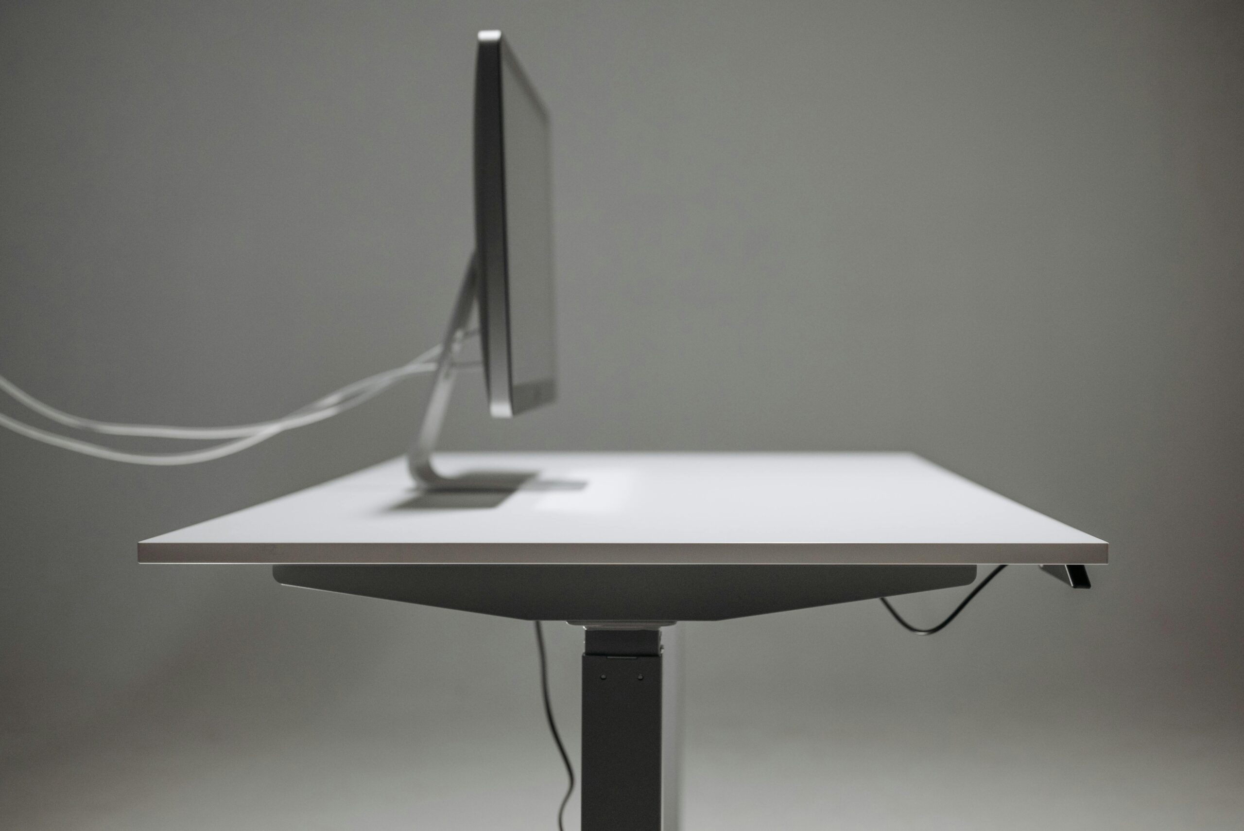 What We Review Side profile of a modern office desk with a computer monitor, emphasizing minimalism and technology.