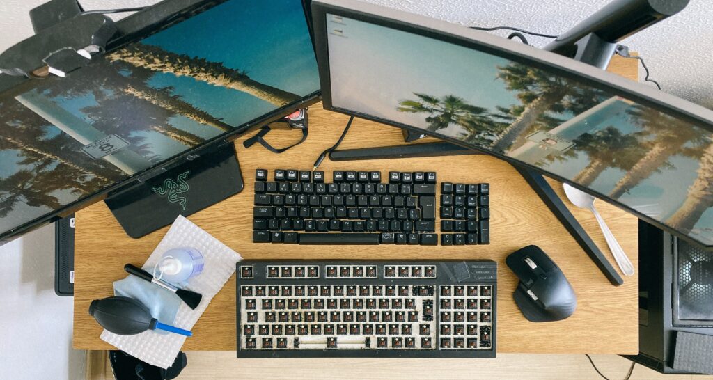 From above of desktop with multi monitors and keyboard with remove keycaps for cleaning