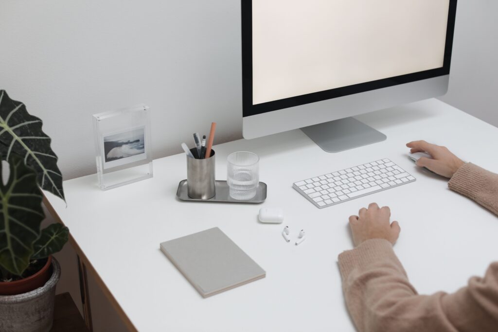 The Exact Desk Height for Typing Comfort High angle of crop faceless person sitting at table with wireless gadgets and computer